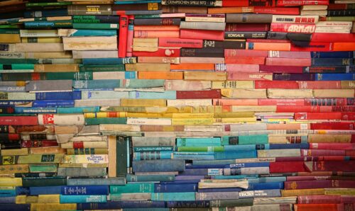 A series of books with colorful spines stacked to form a rainbow pattern