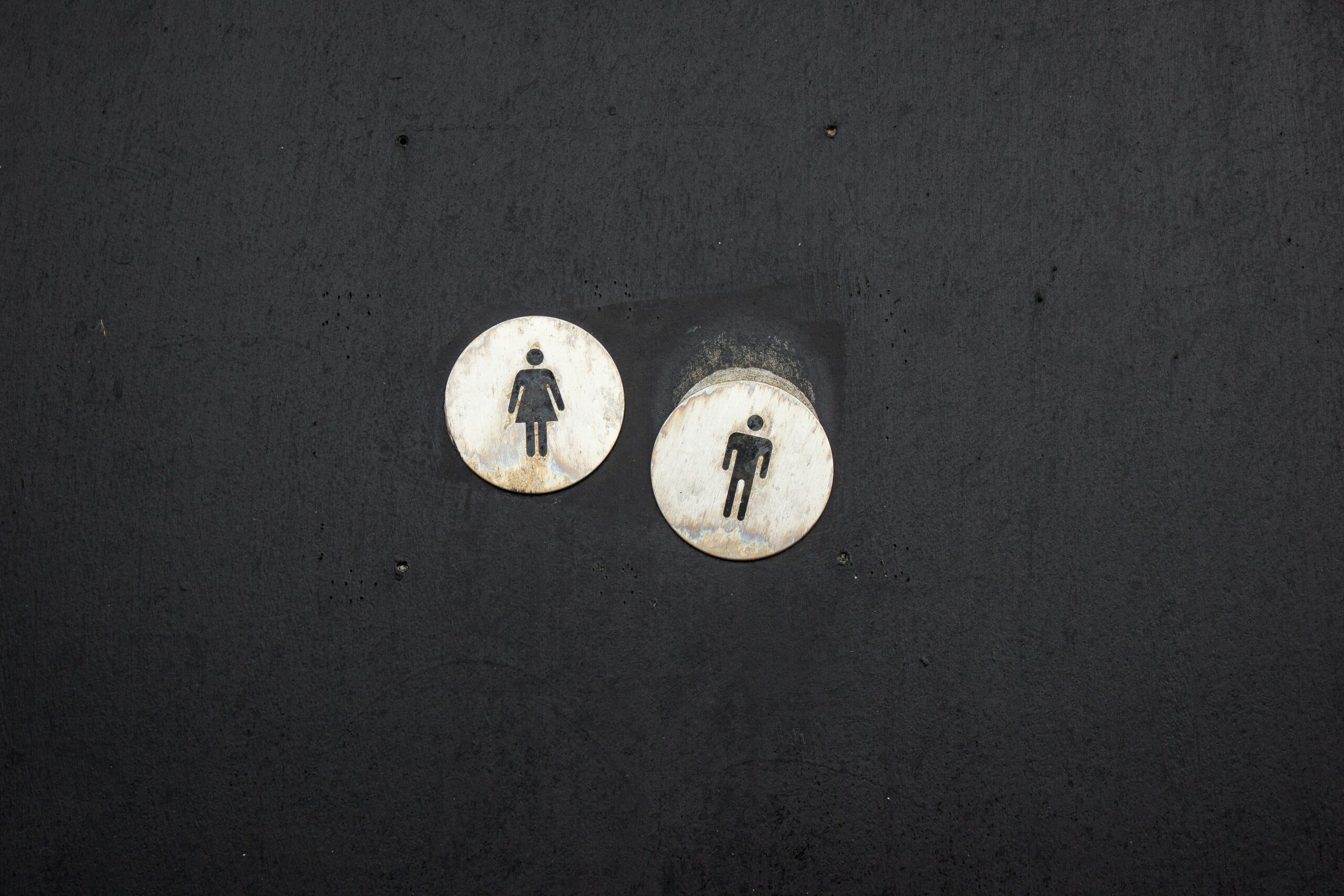 Two gendered restroom signs, slightly askew in space